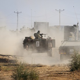 Armored vehicles travel along a dirt track near in Kibbutz Re'im, Israel